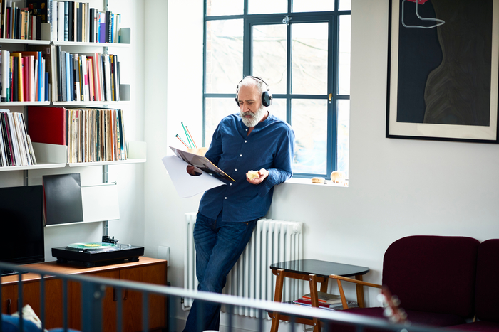 Senior mit Kopfhörern lehnt am Fensterbrett und hört Musik